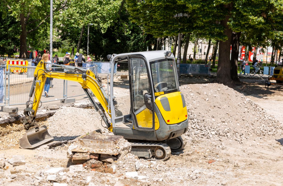 Compact excavator digging and moving material